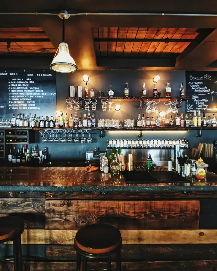 Barra de madera iluminada con botellas al fondo